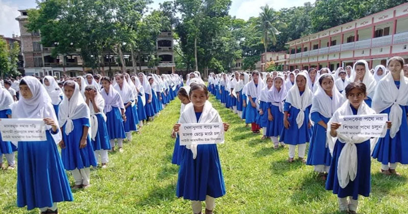 মতলব উত্তরের একটি বিদ্যালয়ে উপবিষ্ট অবস্থায় সকালে সমাবেশে অংশ নিচ্ছে শিক্ষার্থীরা, হাজিরা কমে যাওয়ার প্রেক্ষাপটে সচেতনতা কার্যক্রম জোরদার করা হচ্ছে।